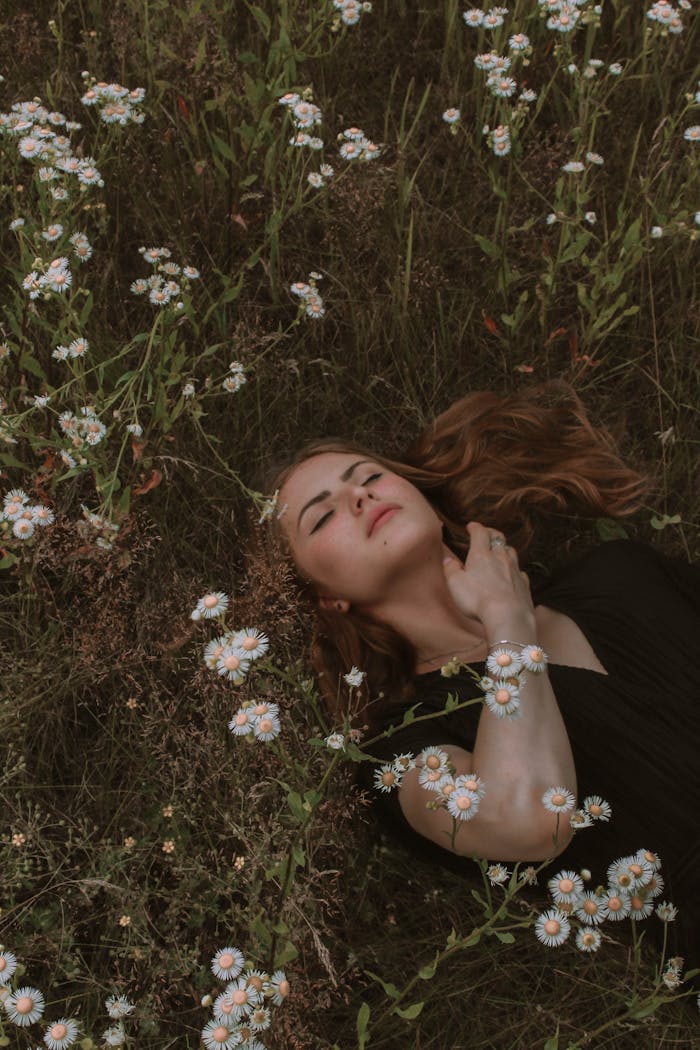 Serene woman lying amidst white wildflowers, evoking peace and nature.